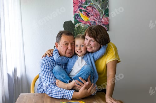 Visualização: Avó, avô e neta felizes se abraçam compartilhando um momento alegre em família.
