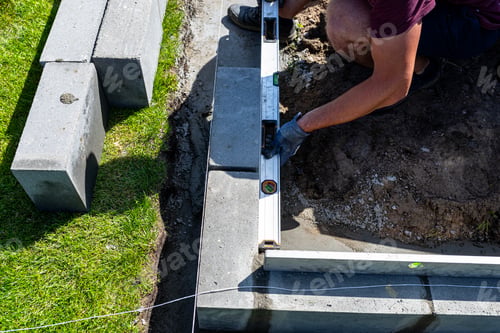 Preview: A man lays concrete blocks on a poured foundation, gluing them with mortar.