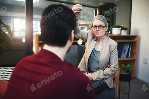 Preview: Shot of a young man being hypnotised during a therapeutic session with a psychologist