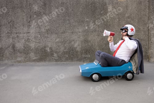 Preview: Funny businessman driving retro pedal car outdoor