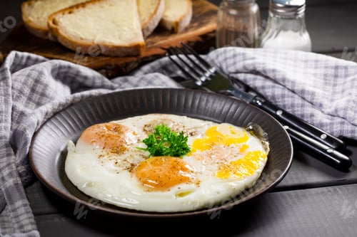 Preview: Fried eggs and bread for breakfast on a gray background.