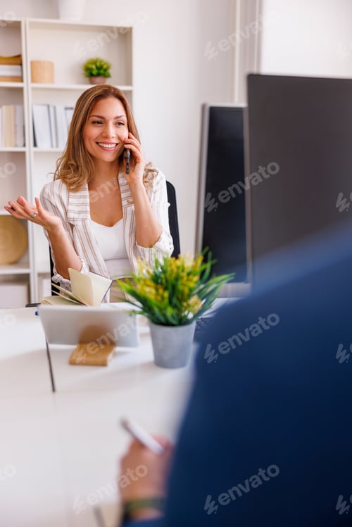 Preview: Business woman speaking on the phone while working in an office
