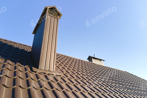 Preview: Chimney on house roof top covered with metallic shingles under construction.