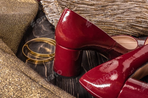 Preview: close up view of fashionable red and golden female shoes and bracelets on wooden tabletop