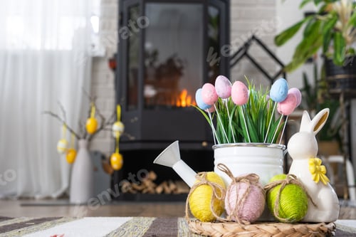 Preview: Easter decor near fireplace stove with fire and firewood. Cozy home hearth in interior with potted p