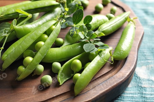 Preview: Wooden board with green peas on table, closeup