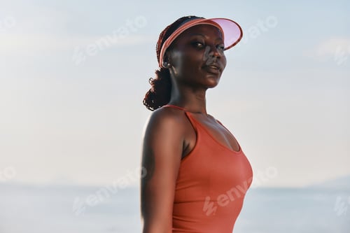 Preview: Confident woman in athletic wear at the beach during sunset