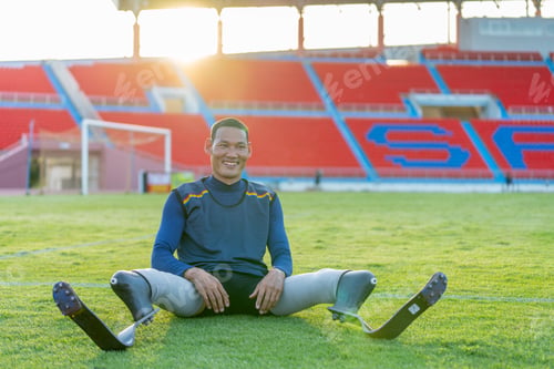 Preview: Sport man athlete prosthesis legs sit down on grass field and separate his legs to relax