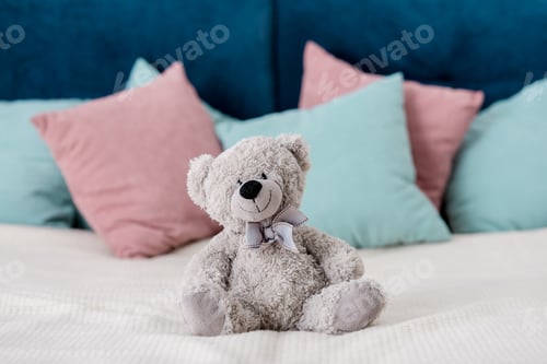 Preview: teddy bear sitting on the bed with pillows on background