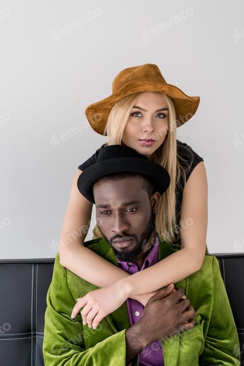 Preview: caucasian woman hugging stylish african american boyfriend on sofa isolated on grey
