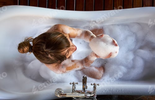 Preview: Woman playing with the foam in a bathtub, from above