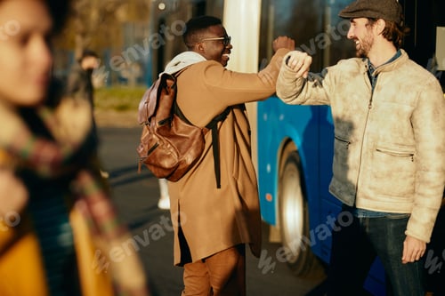 Preview: Happy men elbow bumping while greeting at bus station.