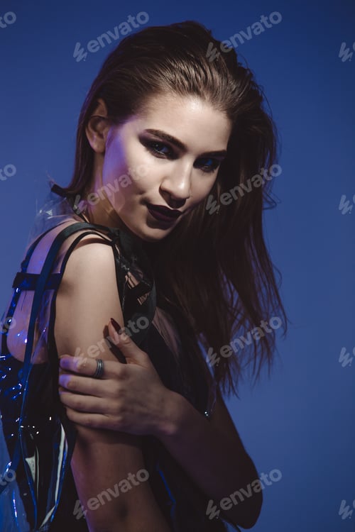 Preview: Stylish model with dark lipstick and wet hair dressed in black swimming suit and transparent rain