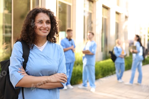 Preview: Happy medical student in uniform with backpack near building outdoors, selective focus