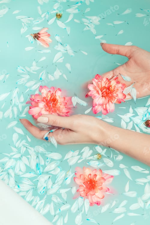 Preview: Women's hands on the background of a bath filled with blue water and decorated with chrysanthemum.