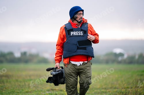 Preview: Reporter in bulletproof vest holding a video camera