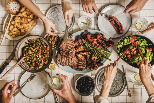 Preview: Flat-lay of people having dinner with frilled meat and vegetables