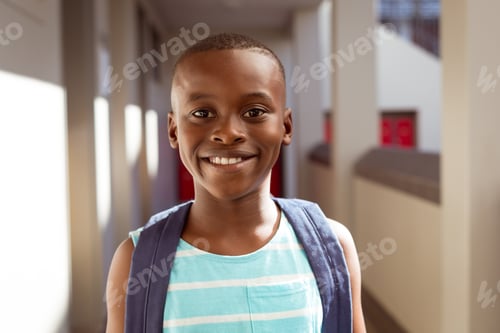 Preview: Portrait of smiling african american schoolboy wearing schoolbag standing in school corridor