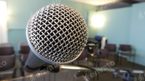 Preview: Microphone at the front of an empty room where a speech will be given. Chairs are empty. No People.