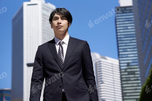 Preview: A Japanese male businessman walks through an office district.