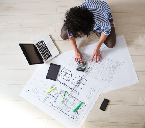 Preview: Female architect studying plans in office, she drawing with pencil and ruler.