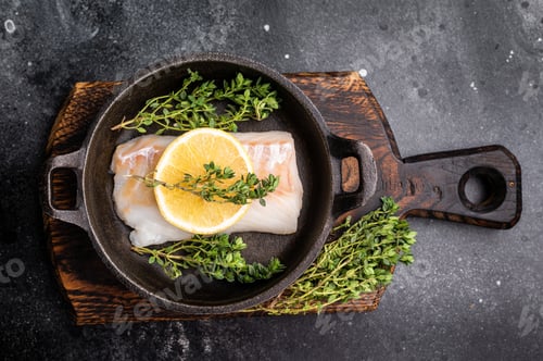 Preview: Raw cod fish fillets, whitefish without skin in skillet. black background. top view