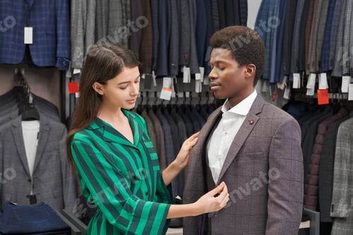 Preview: Woman Helping Man Choose Suit at Clothing Store