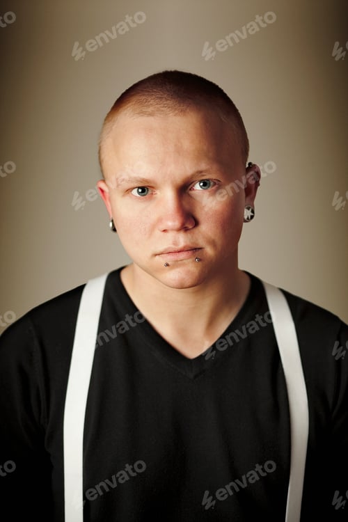 Preview: Portrait of young man with piercing standing against wall