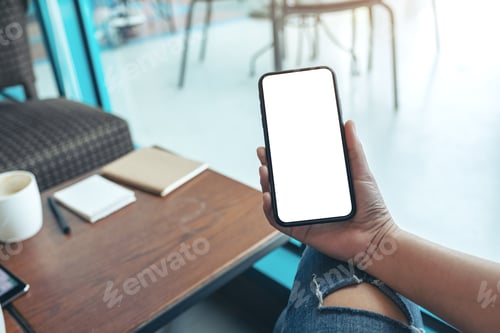 Preview: Mockup image of woman's hands holding black mobile phone with blank white screen in cafe