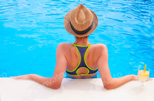Preview: Pretty brunette woman enjoying lemonade in a swimming pool