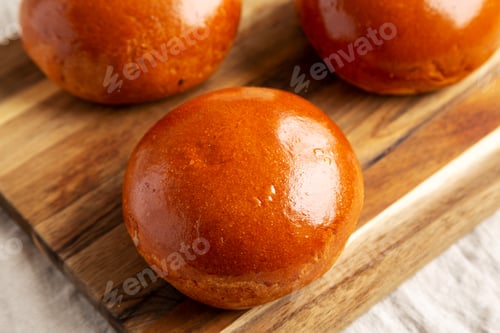 Preview: Homemade Brioche Hamburger Buns on a wooden board, side view. Close-up.
