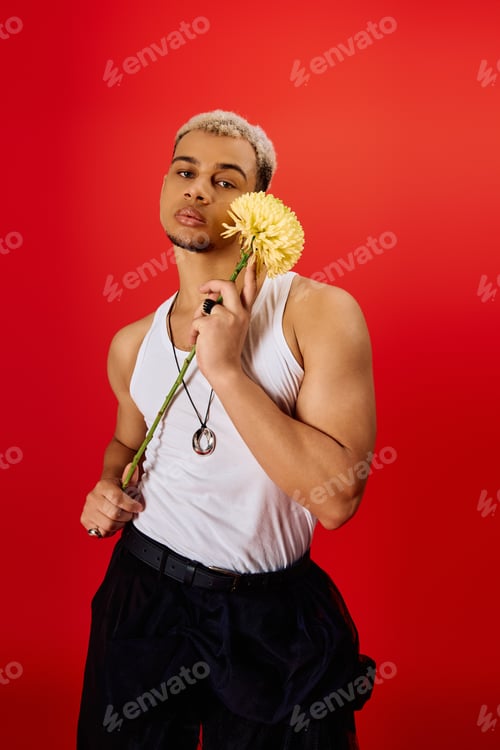 Preview: Young man showcases trendy style in red studio with vibrant flower