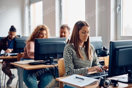 Preview: Mid adult woman e-learning on a computer during class in the classroom.