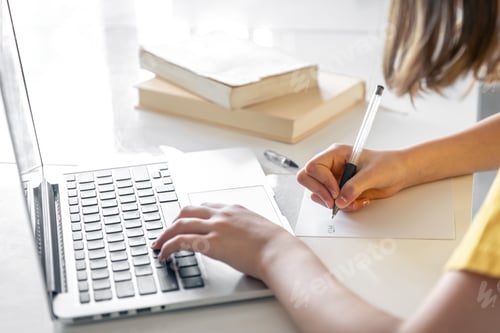 Preview: A teenage girl does her homework while sitting with books and a laptop.