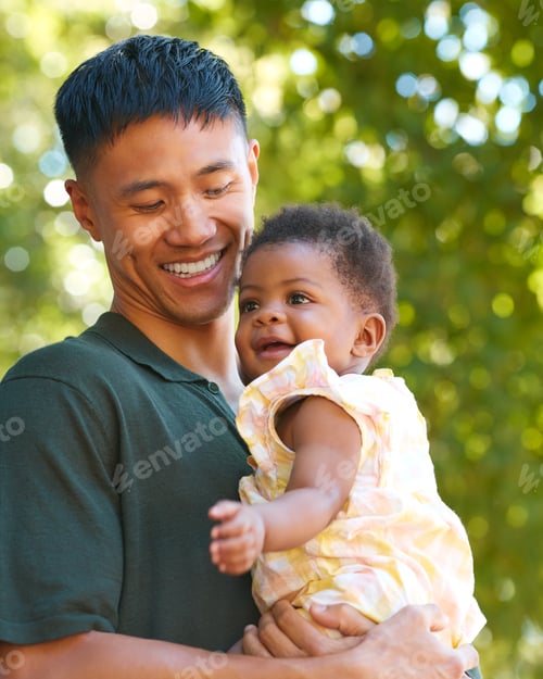 Preview: Family Shot With Loving Father Cuddling Baby Daughter Outdoors In Garden Or Countryside
