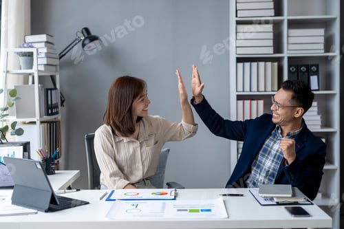 Preview: Two people are high fiving each other in a business setting