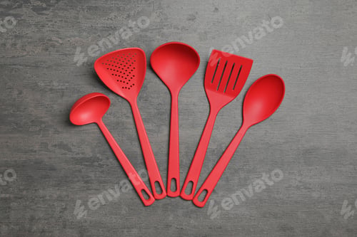 Preview: Set of red cooking utensils on grey table, flat lay