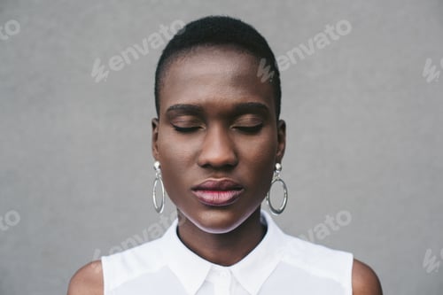 Preview: portrait of stylish attractive african american woman standing with closed eyes near grey wall
