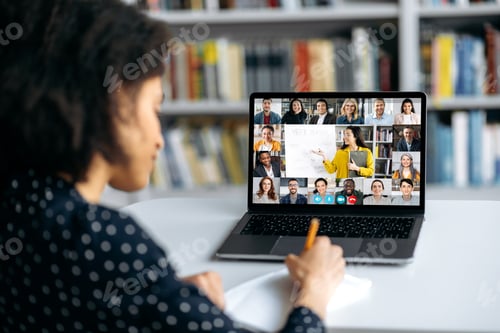 Preview: View over shoulder of an mixed race clever female student at a laptop screen with a female teacher