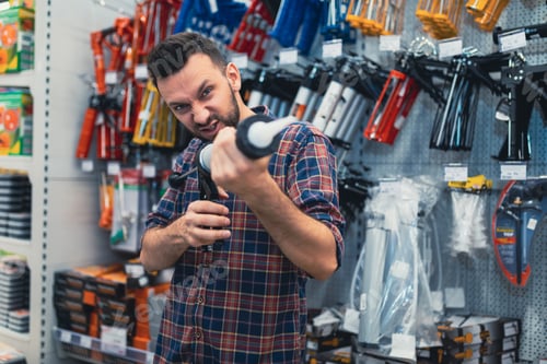 Preview: shoppers in a hardware store kidding with a construction gun for glue sealant