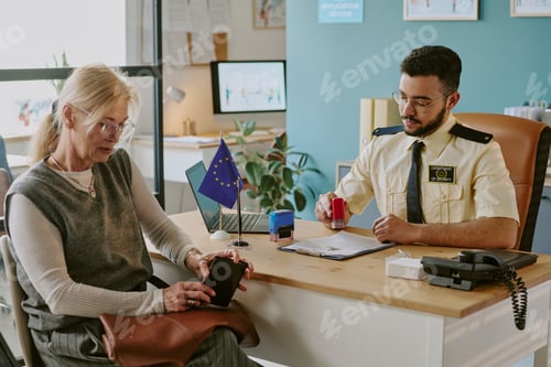 Preview: Senior Woman Sitting at Immigration Office with Officer
