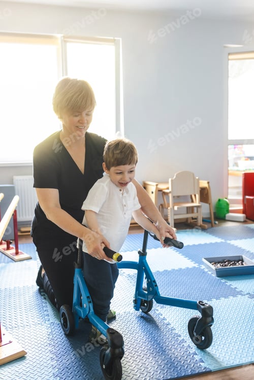 Preview: Physical therapist assists a young boy with movement disorders as he engages in physical