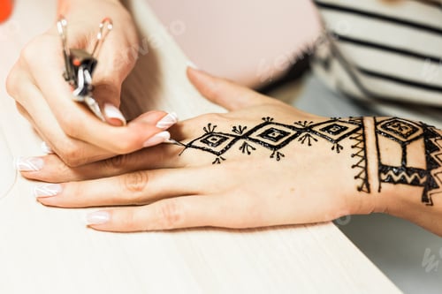 Preview: young woman mehendi artist painting henna on the hand