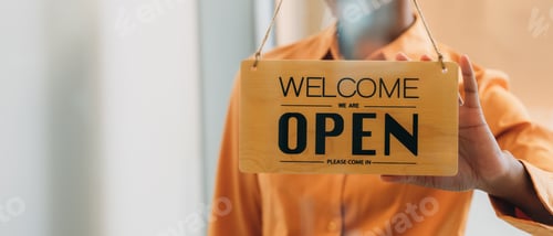 Preview: Woman setting open sign board through the door glass.