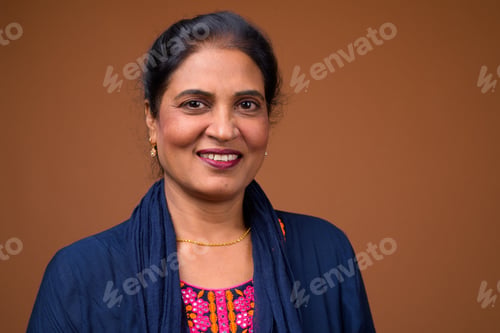 Preview: Face of beautiful Indian woman smiling against brown background