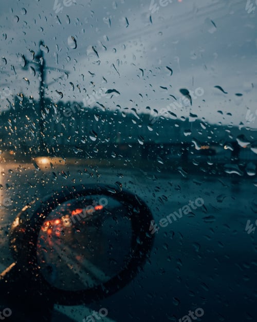 Preview: Raindsrops outside car with auto mirror, unrecognizable driver drives car at bad weather