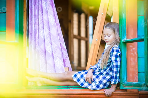 Preview: Adorable little girl in the window of rural house outdoors