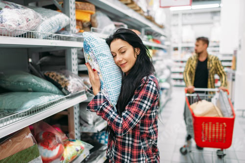 Preview: Young couple choosing pillow in supermarket