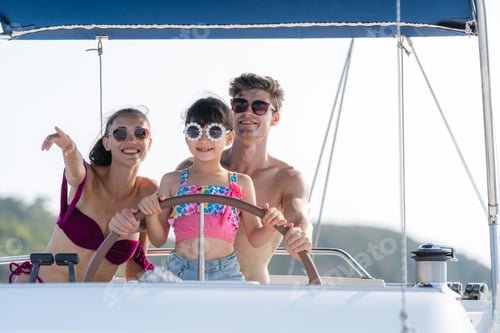 Preview: Mother and Father teaching their daughter how to drive speedboat or yacht, concept of family
