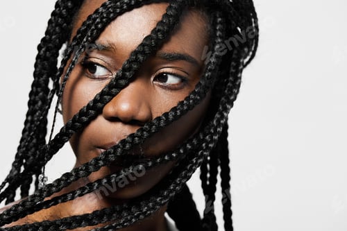 Preview: Close up portrait of a young Black woman with braided hair, showcasing her thoughtful expression